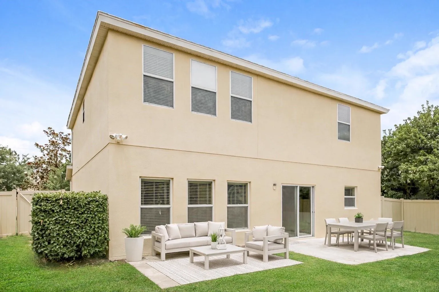 Rear exterior of the Cheval Street home in Mount Dora, Florida, showing the two-story stucco exterior and a patio with outdoor seating overlooking the backyard