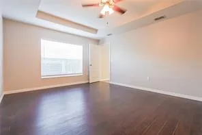 Bedroom at the Tee Shot Drive home with a tray ceiling and dark wood-look flooring